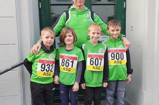 Gruppenshooting mit vier Kindern in gr&uuml;nen Sporttrikots und einem Erwachsenen vor einer Eingangst&uuml;r.