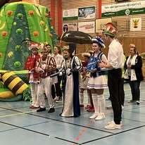 Gruppe von kost&uuml;mierten Personen steht vor einem aufblasbaren Spielger&auml;t in einer Sporthalle.