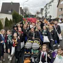 Gruppe von Menschen in Kost&uuml;men, die fr&ouml;hlich auf einer Stra&szlig;e w&auml;hrend eines Festumzugs posieren.