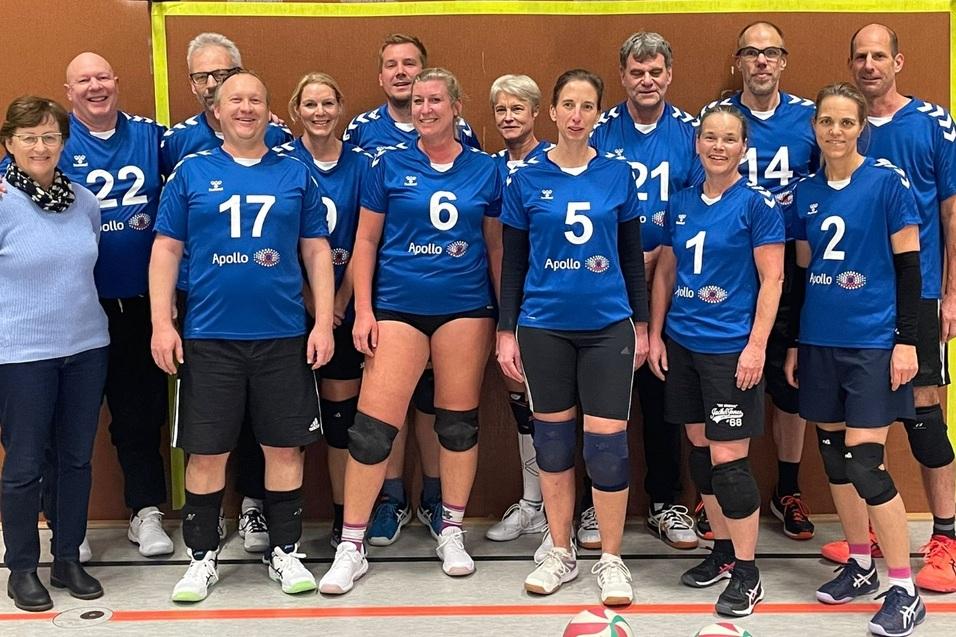 Gruppe von Volleyballspielern in blauen Trikots mit der Aufschrift „Apollo“, auf einem Sportplatz versammelt.