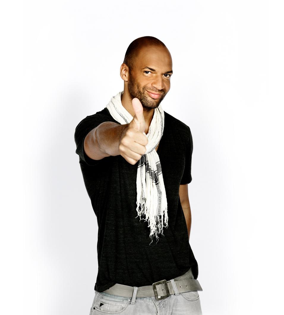 Mann mit dunkler Kleidung und Schal gibt Daumen hoch vor wei&szlig;em Hintergrund.