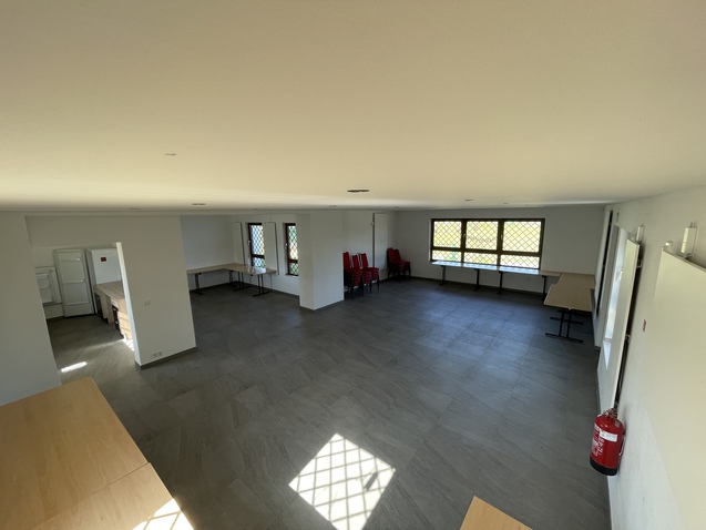 Blick auf einen lichtvollen Raum mit Tischen, St&uuml;hlen und Fenstern, ausgestattet f&uuml;r Veranstaltungen.